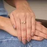 mulher-usando-anel-em-ouro-amarelo-18k-aro-com-pedras-de-zirconias-brancas-com-duas-gotas-de-ouro-no-centro.