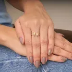 mulher-usando-anel-em-ouro-amarelo-18k-aro-com-pedras-de-zirconias-brancas-com-duas-gotas-de-ouro-no-centro.